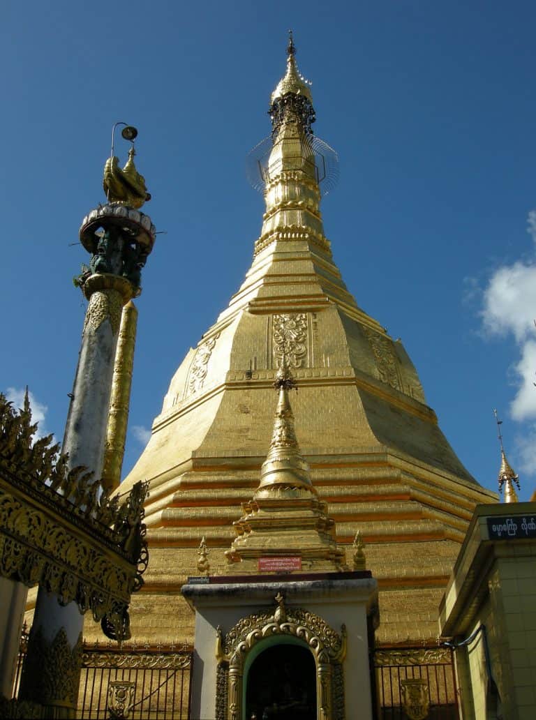 A golden pagoda in Myanmar with a blue sky behind it.