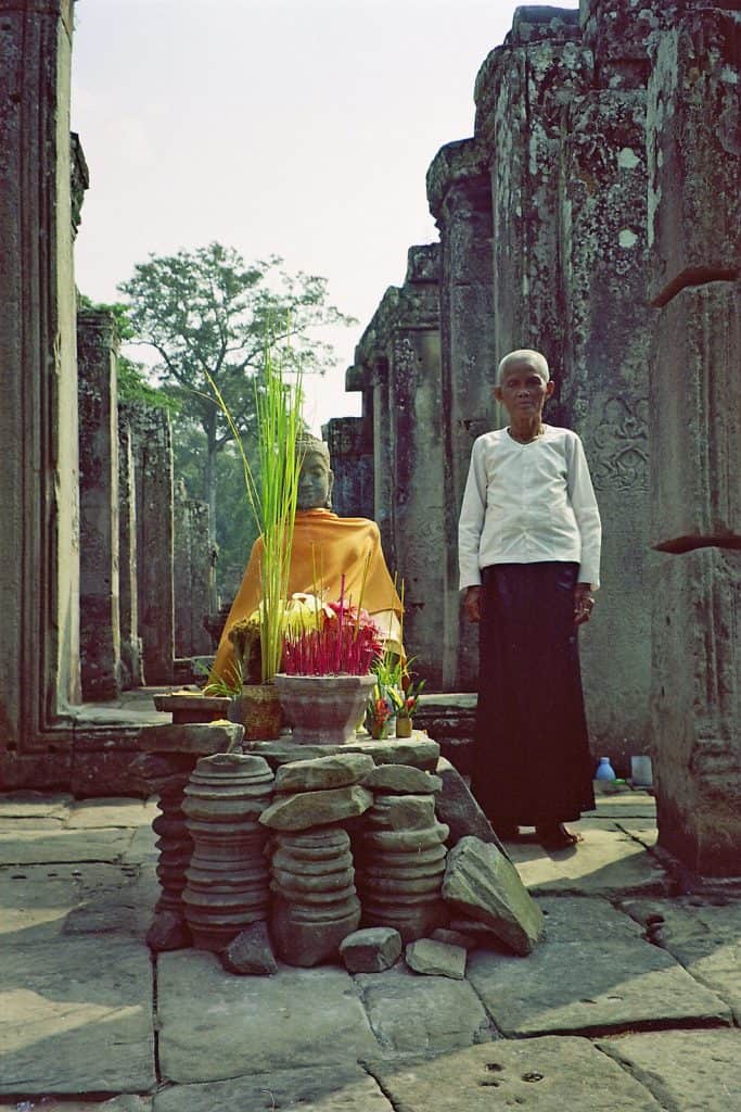 old lady at Buddha statue at Bayon Angkor Park