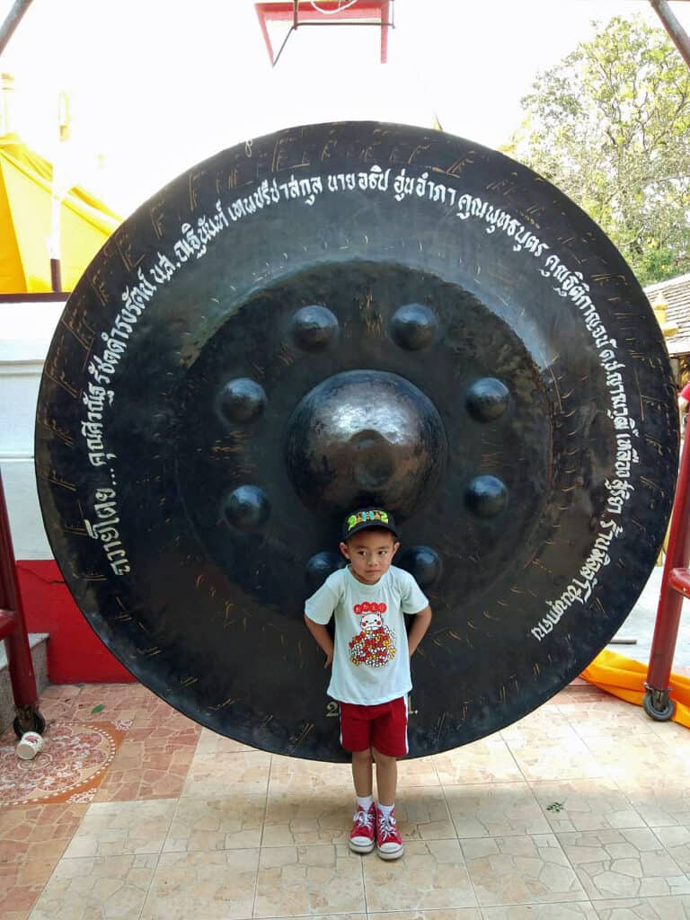 boy in front of huge gong in Wat Doi Kham