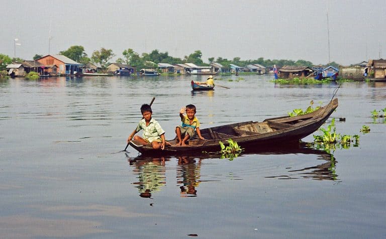 children waving at Tonle Sap lake during river trip to Battambang